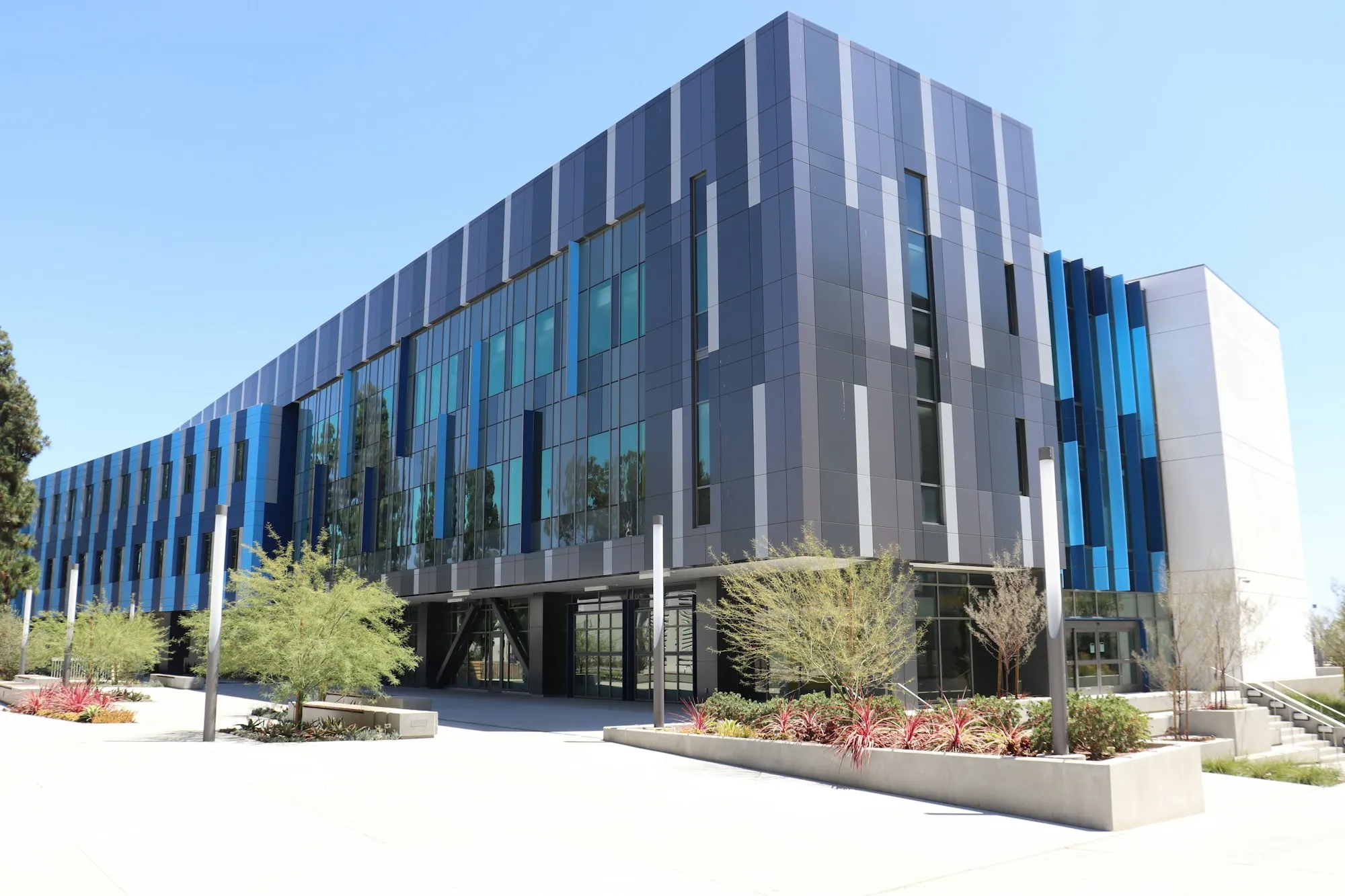 Modern office building with blue facade panels and landscaping