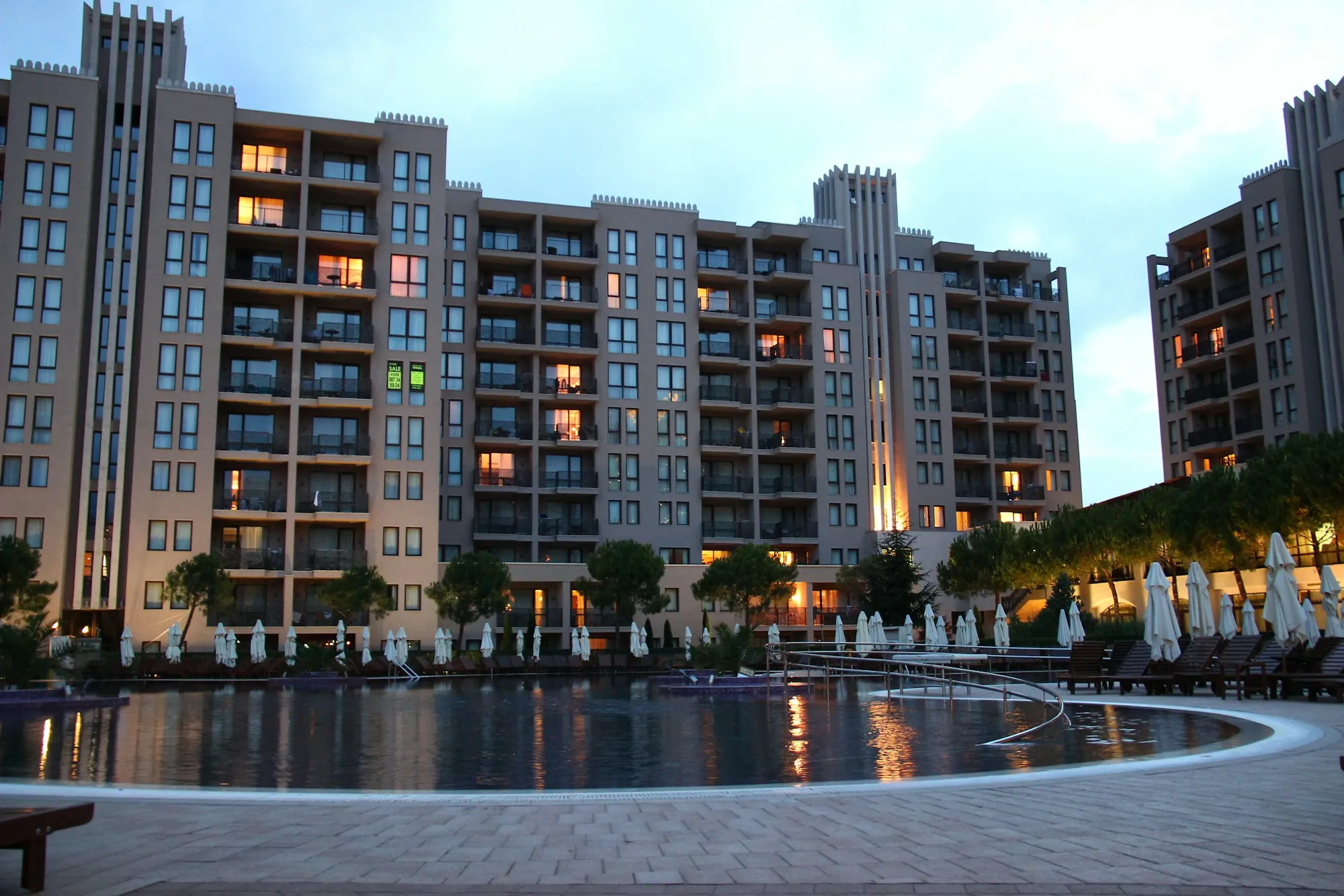 Apartment complex with a pool lit in the evening