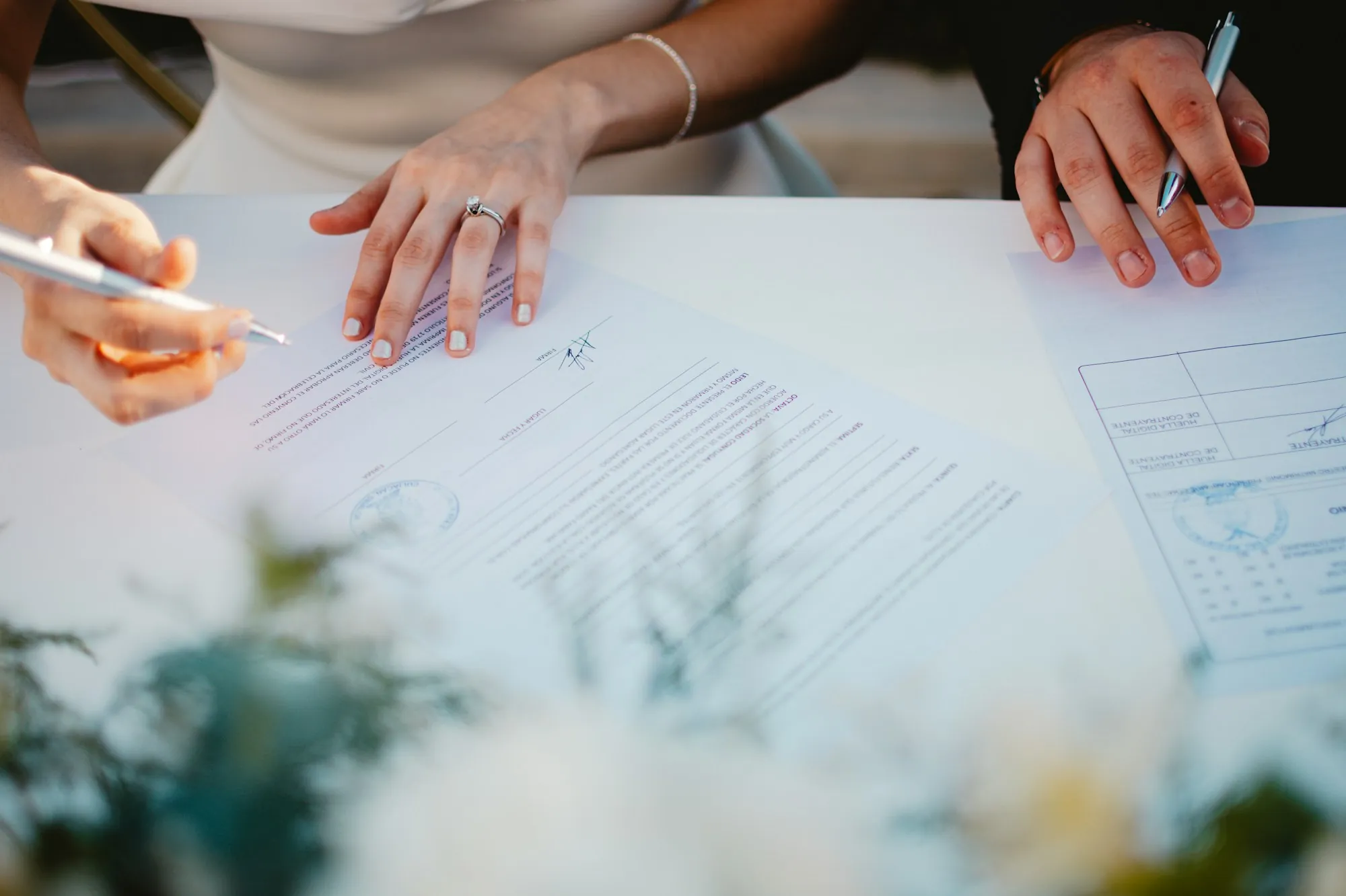 Two people's hands signing papers at a table